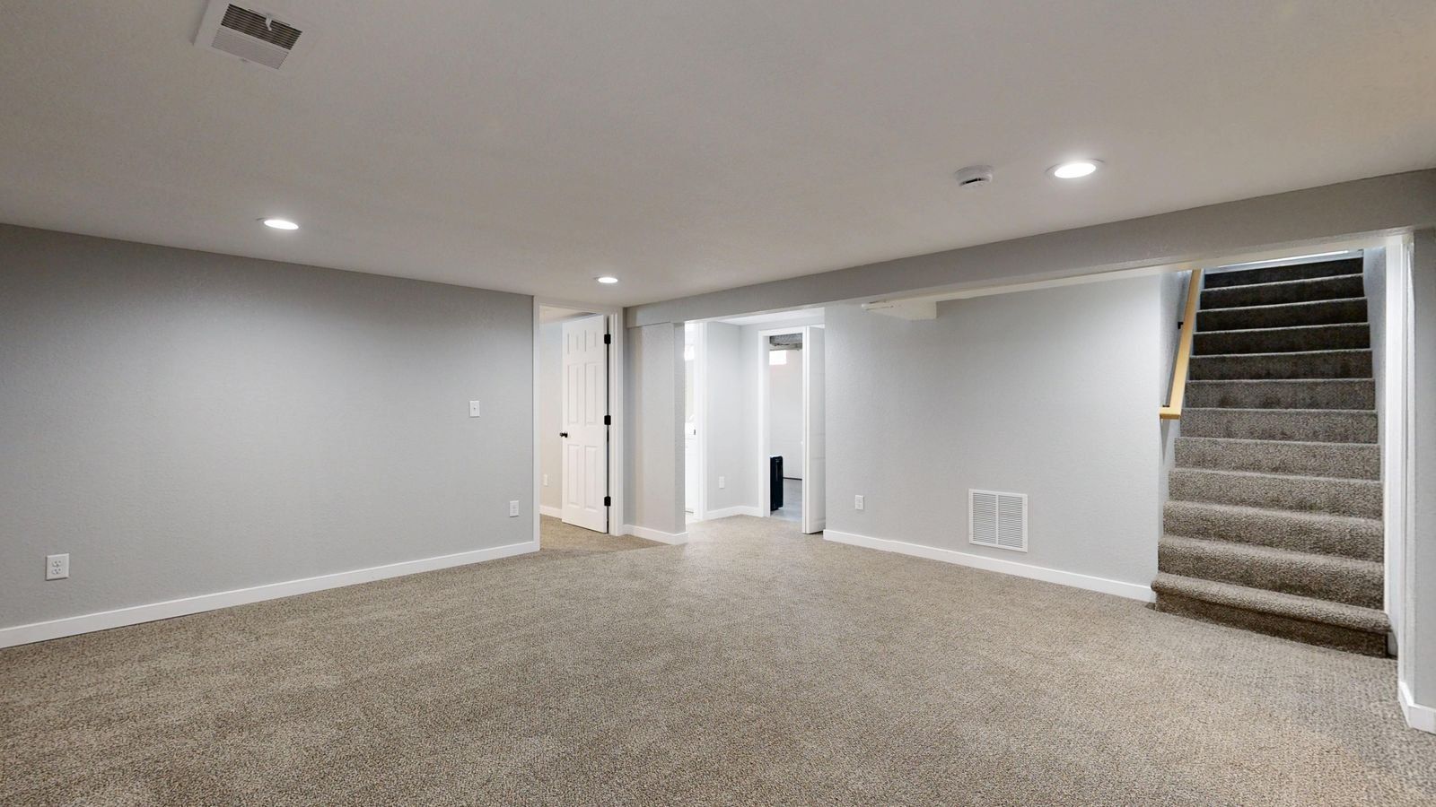 Finished basement interior with bright ceiling lighting and stairs