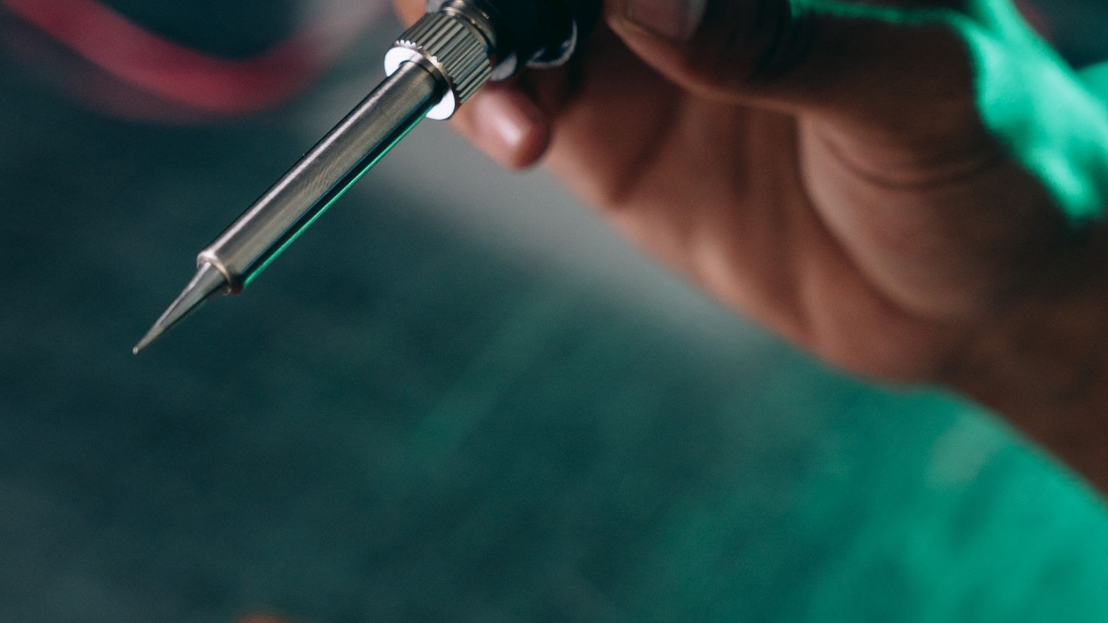 Technician soldering electronic components at a workbench with smoke rising