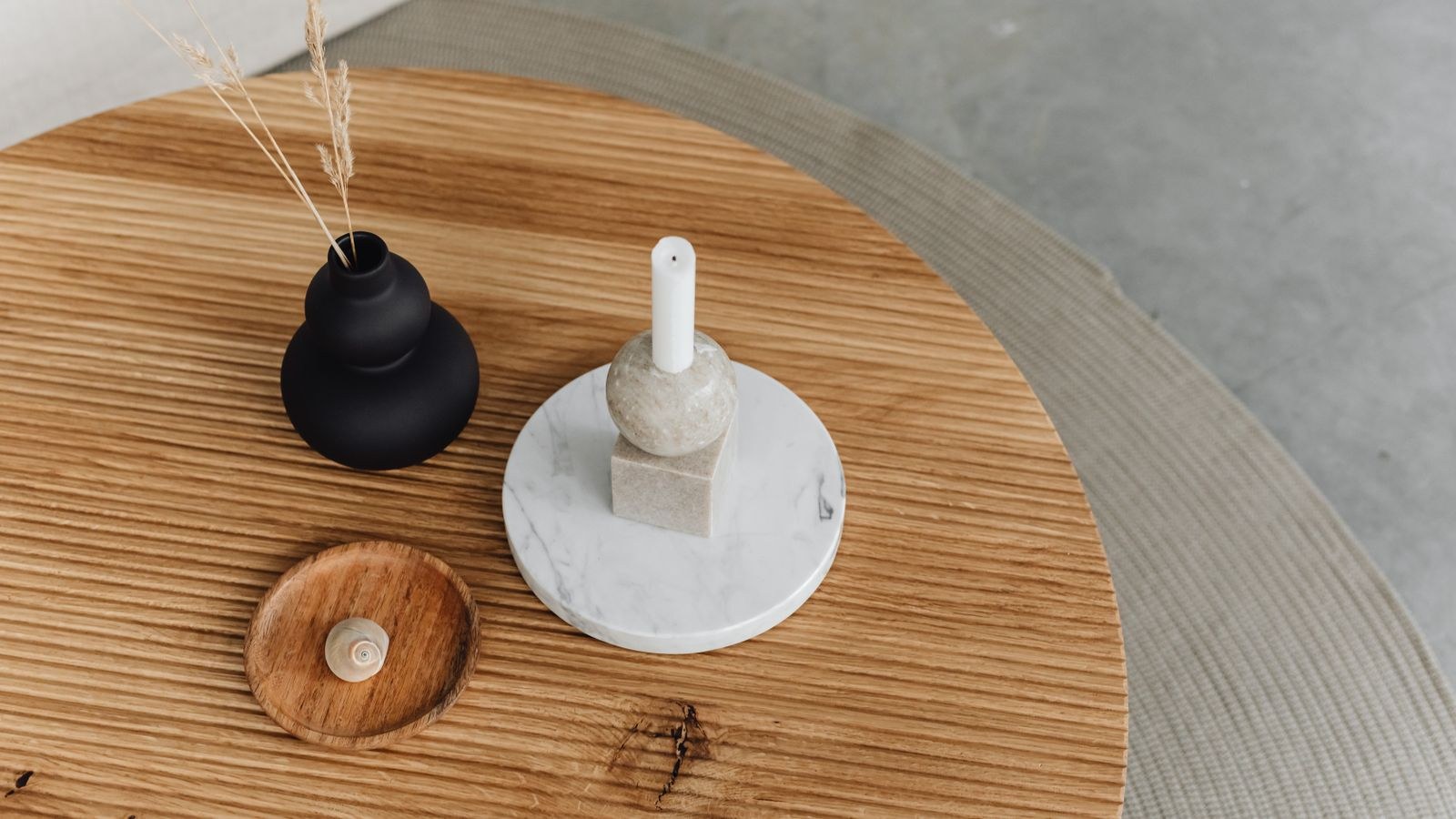 Round coffee table styled with a tray candle and plant beside a sofa