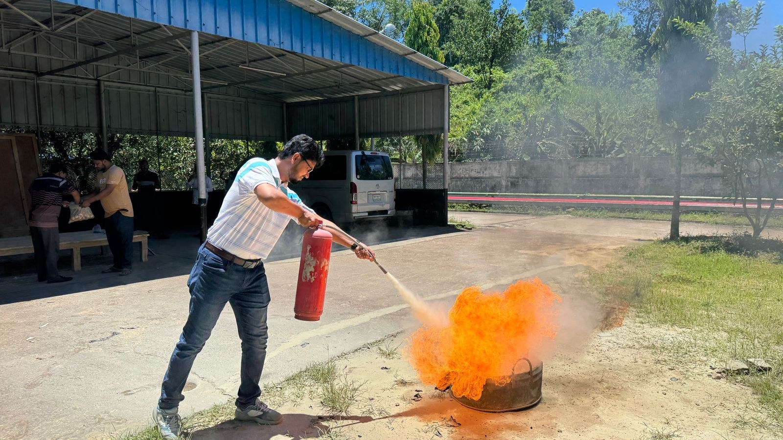 Fire safety training demonstration showing correct extinguisher technique on a controlled fire