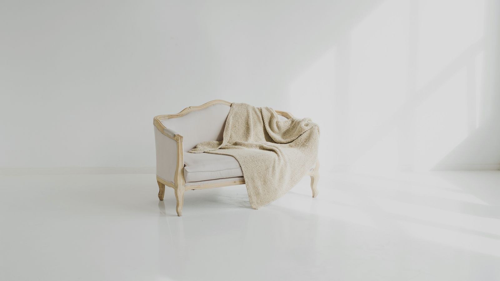 Freshly washed white sofa cover fitted on a sofa with a beige throw
