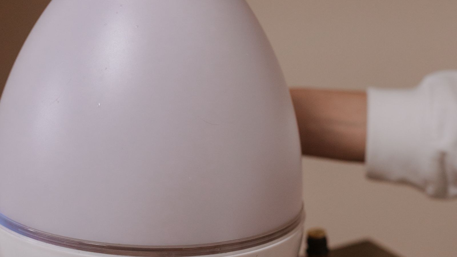 Modern cool mist humidifier releasing vapor on a wooden table indoors