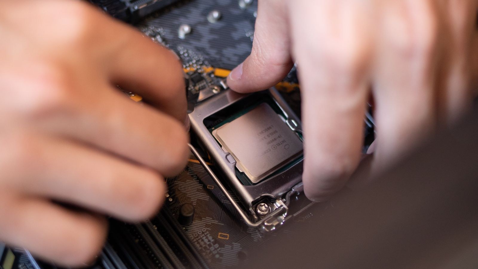 Hands installing a processor onto a computer motherboard during a PC build