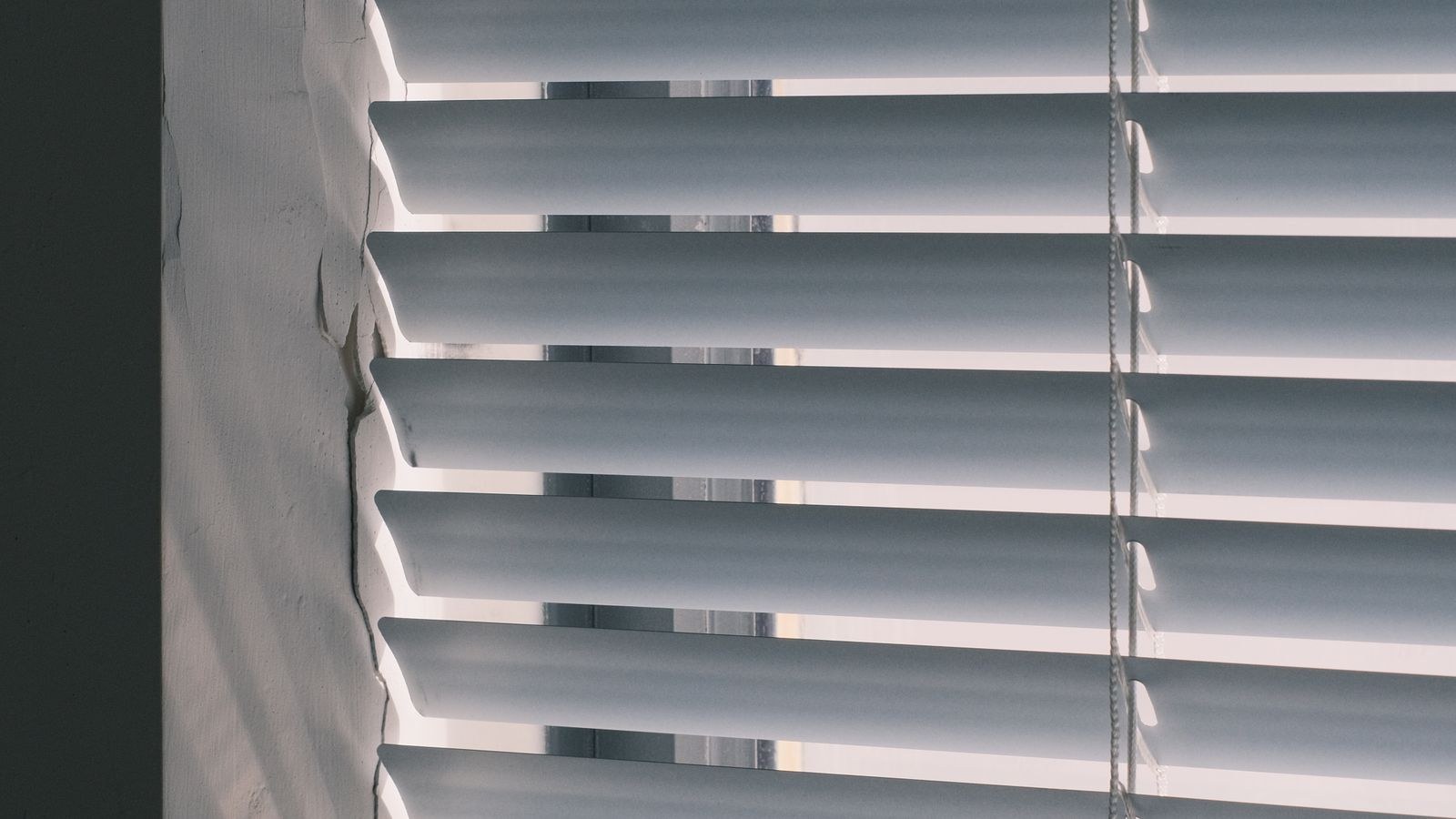 Close up of white horizontal window blinds with light filtering through