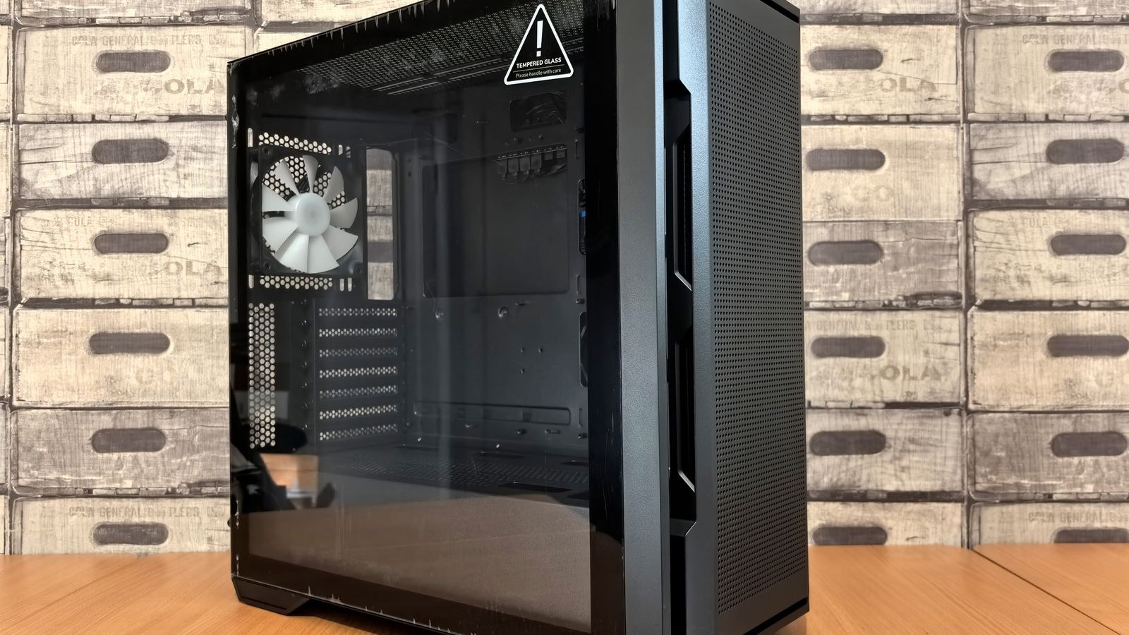 Tempered glass PC case on a desk showing clearance for a vertical GPU mount