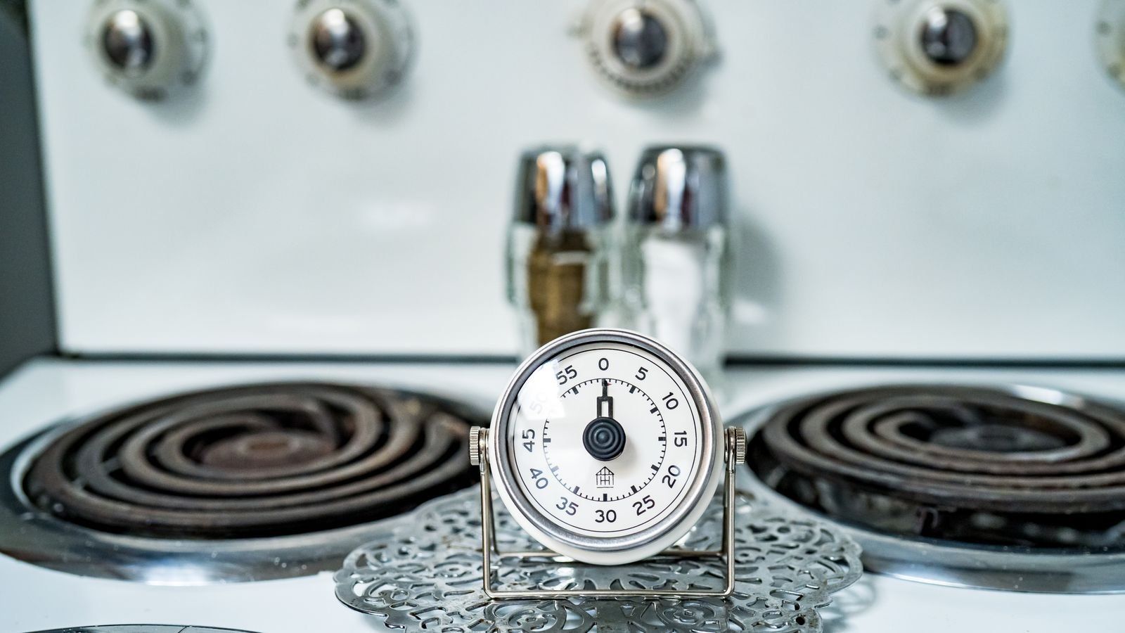 Classic analog mechanical kitchen timer sitting on a stove top