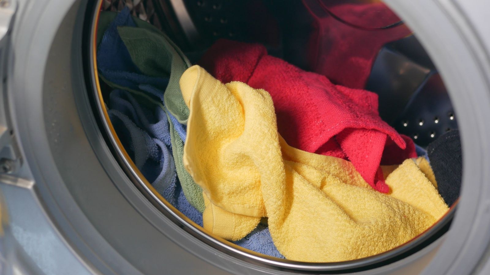 Colourful towels tumbling inside a washing machine drum during a wash cycle