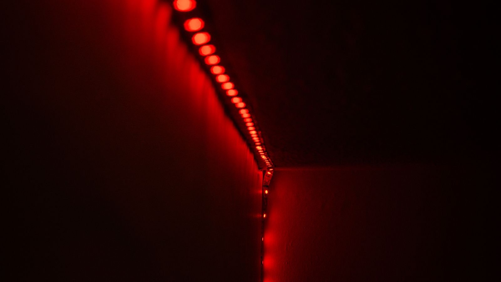 Warm LED strip lighting behind a bedroom headboard