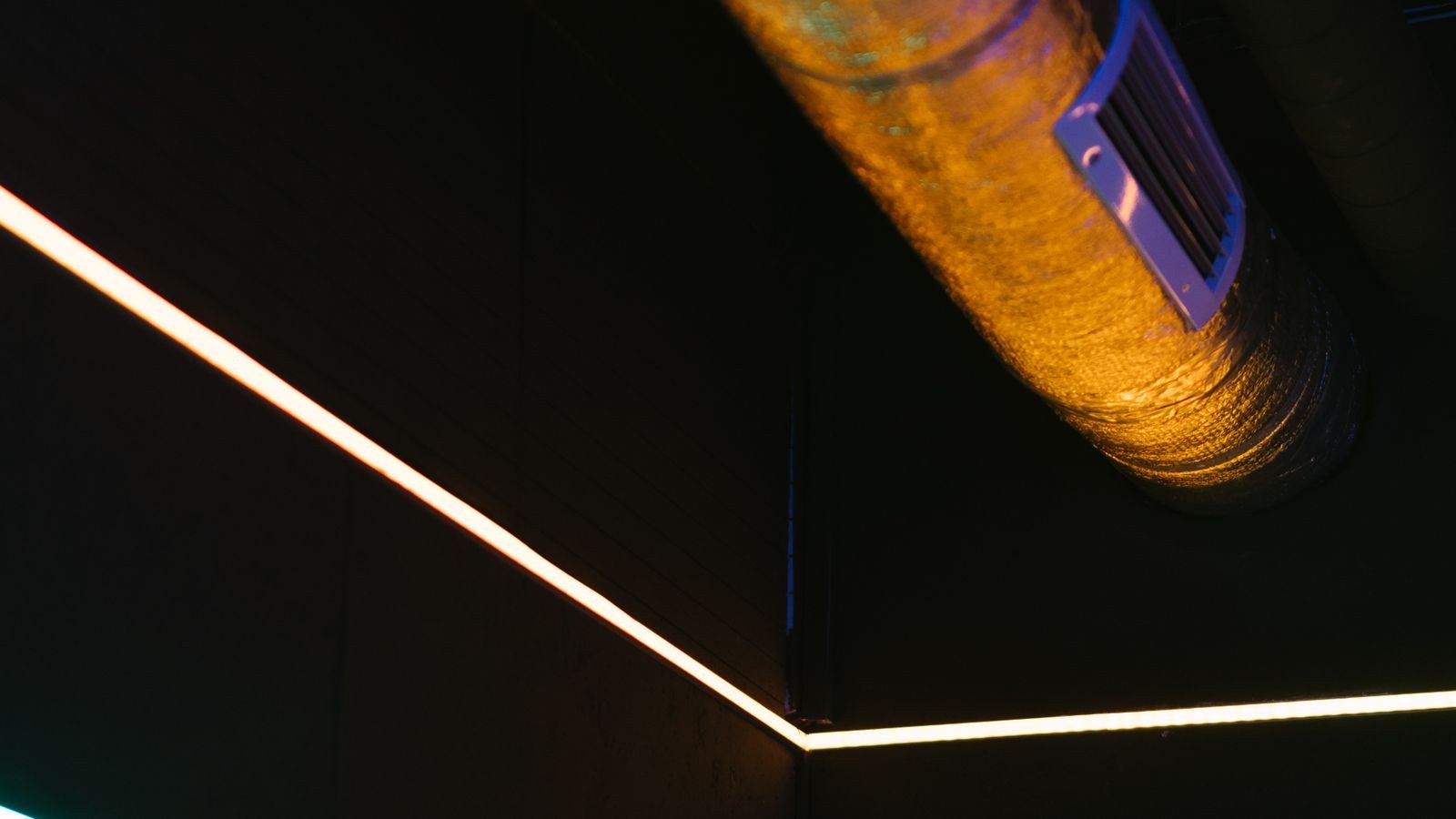 Strip lighting mounted along a ceiling with exposed metal pipes