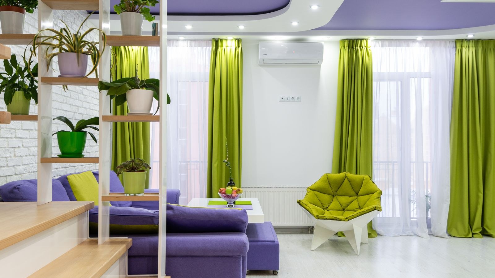 Living room color scheme with a purple sofa, green armchair and potted plants