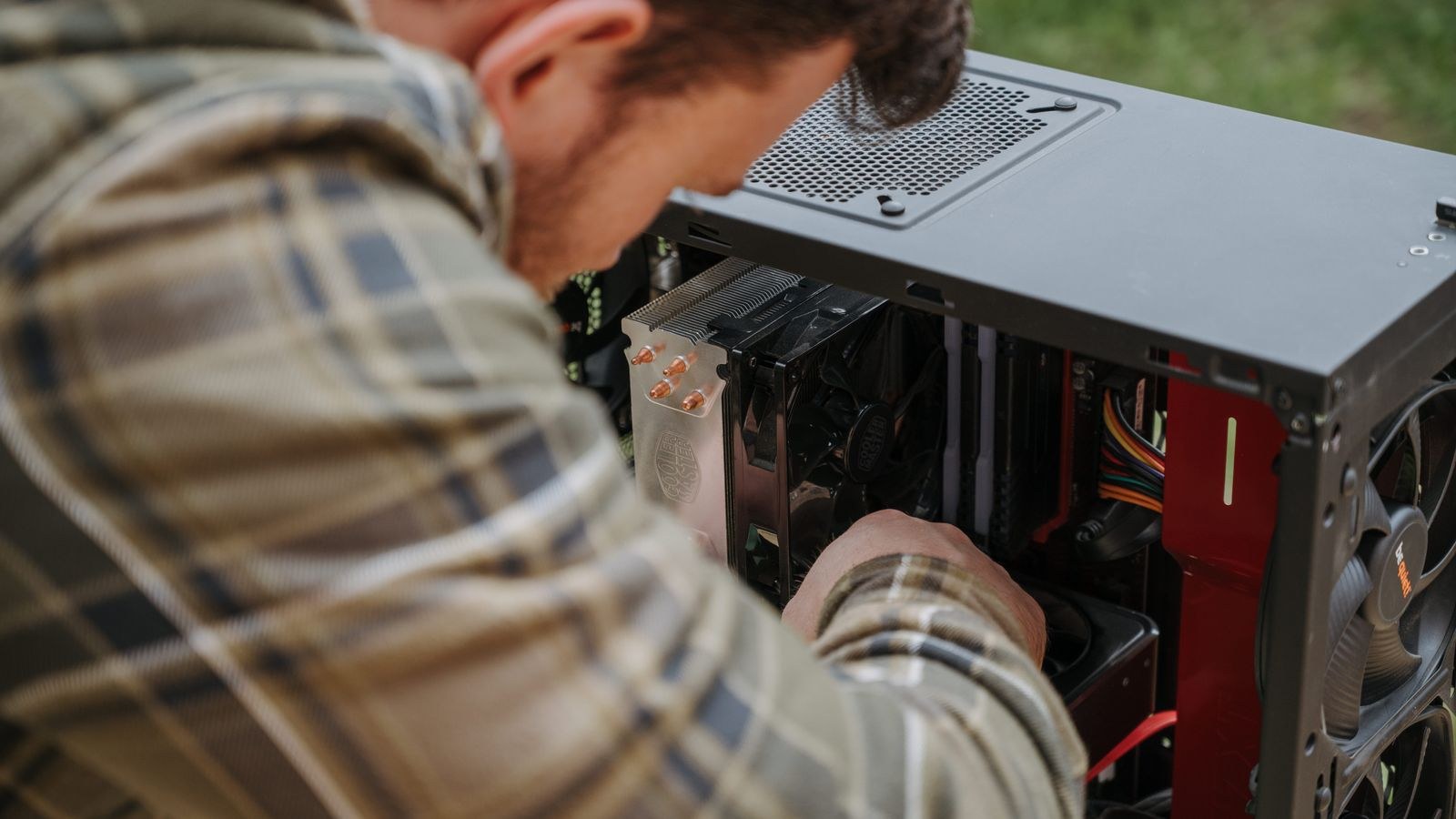 Person cleaning dust from the inside of a desktop PC to improve cooling