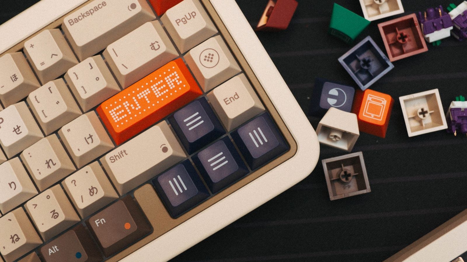 Beige mechanical keyboard viewed from above with loose switches and custom keycaps