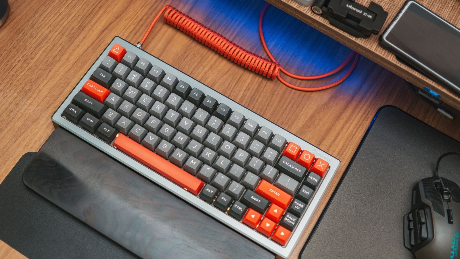 Mechanical keyboard with red accents on a wooden desk viewed from above