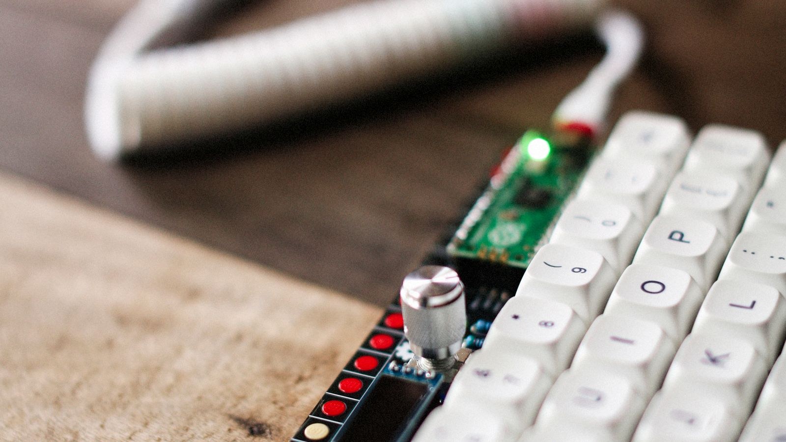 Custom mechanical keyboard with white keycaps on a wooden desk surface