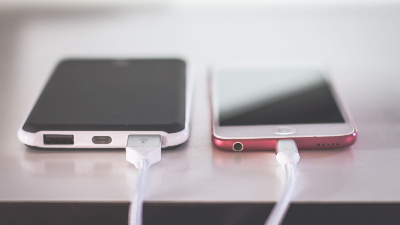 Smartphone plugged into a wall outlet with a USB charging cable