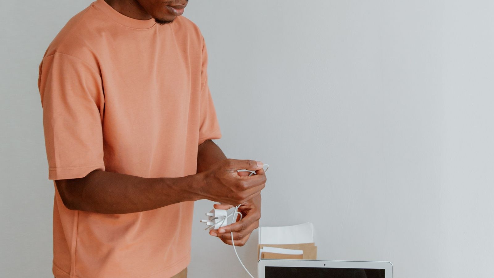 Person organizing charging cables and accessories at a tidy minimalist office desk