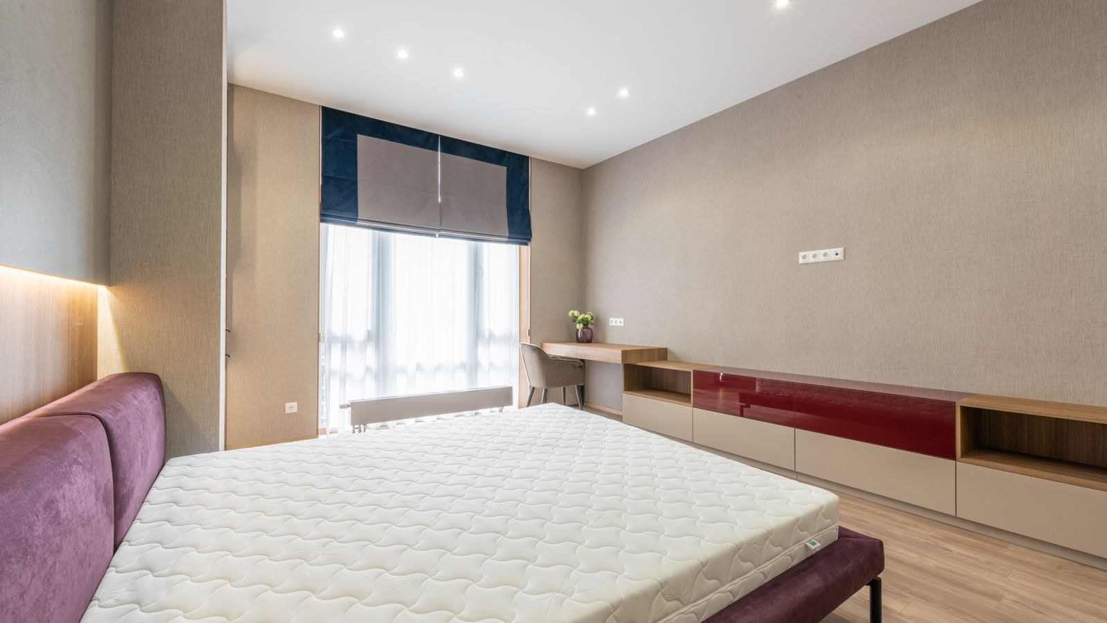 Modern bedroom with a white mattress and topper against a wooden cabinet