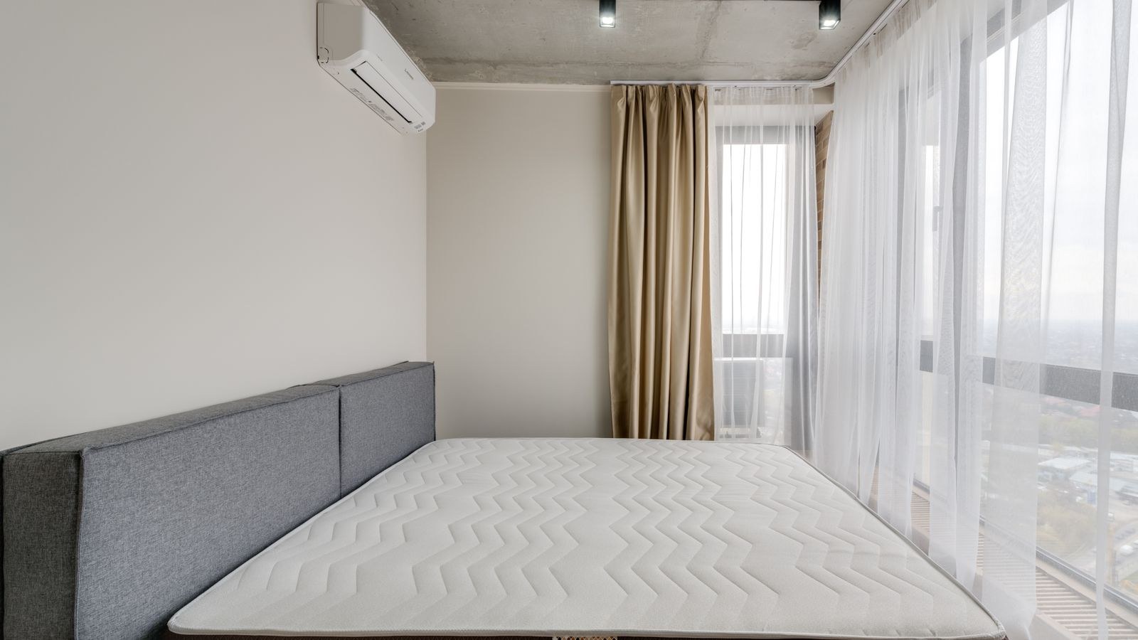 Spacious modern bedroom with a clean mattress and topper in natural light