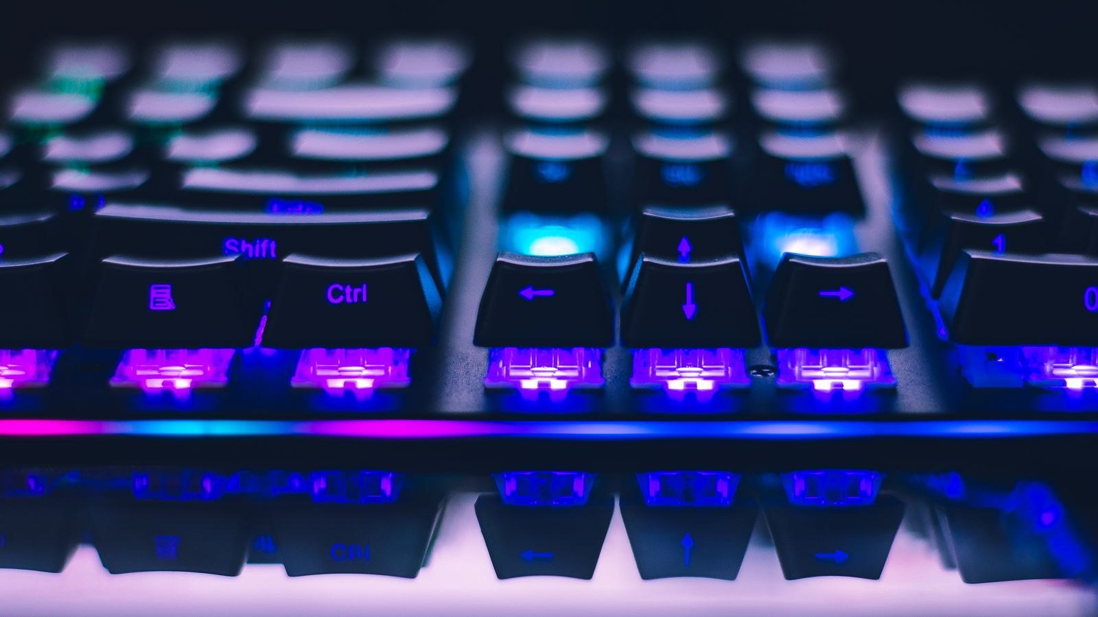 Illuminated mechanical keyboard keys glowing with blue and purple backlighting