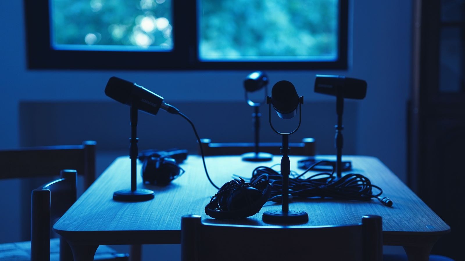 Dimly lit podcast studio with microphones and headphones on a table