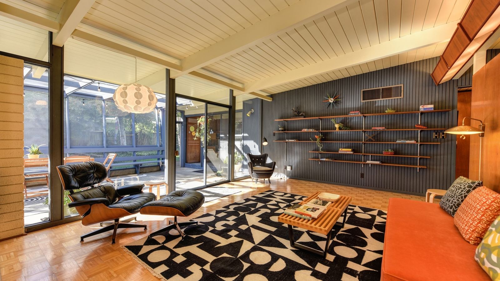 Mid-century modern living room with armchairs, shelving and natural light