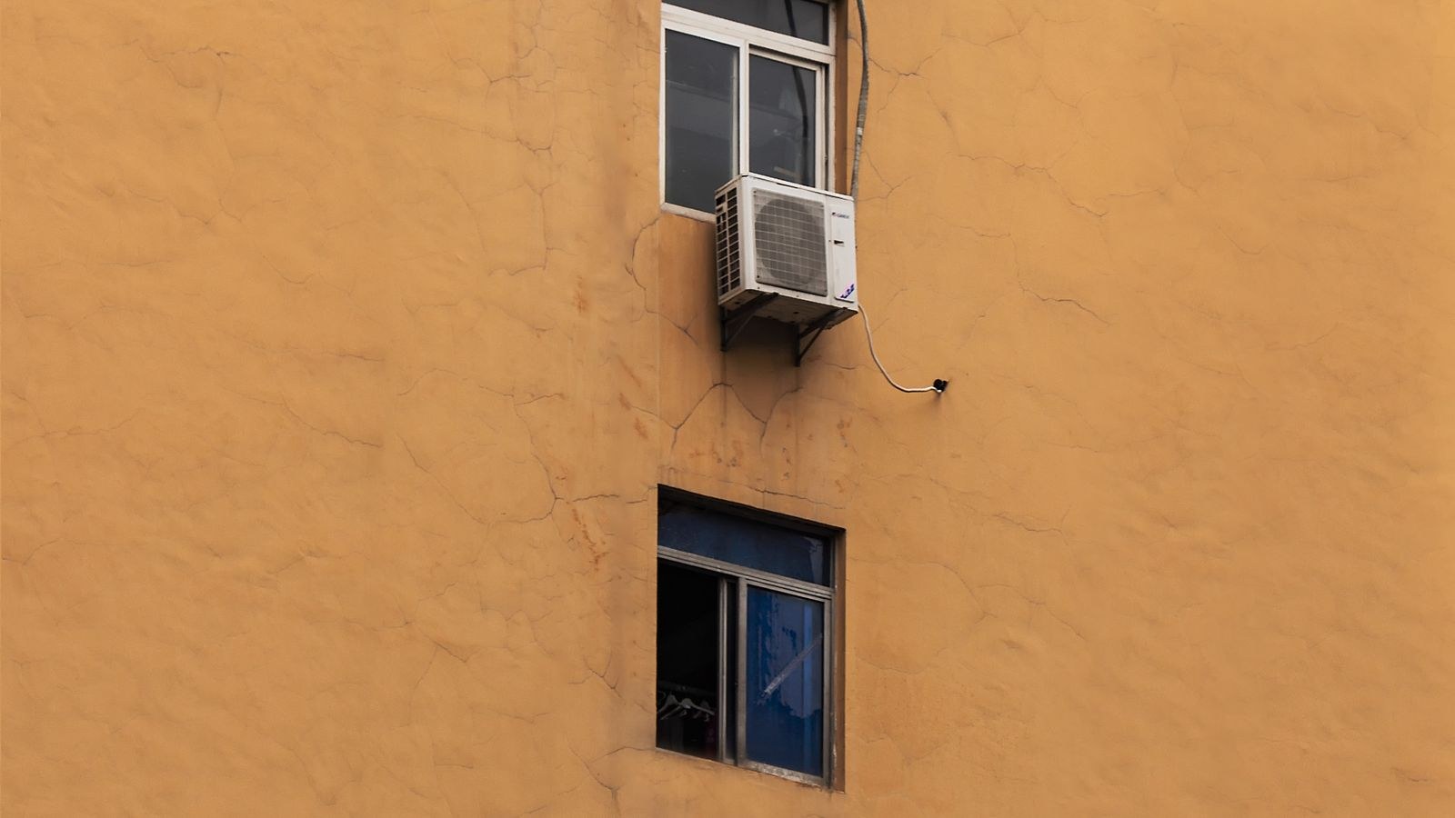 Building facade showing numerous window air conditioners installed on apartment windows