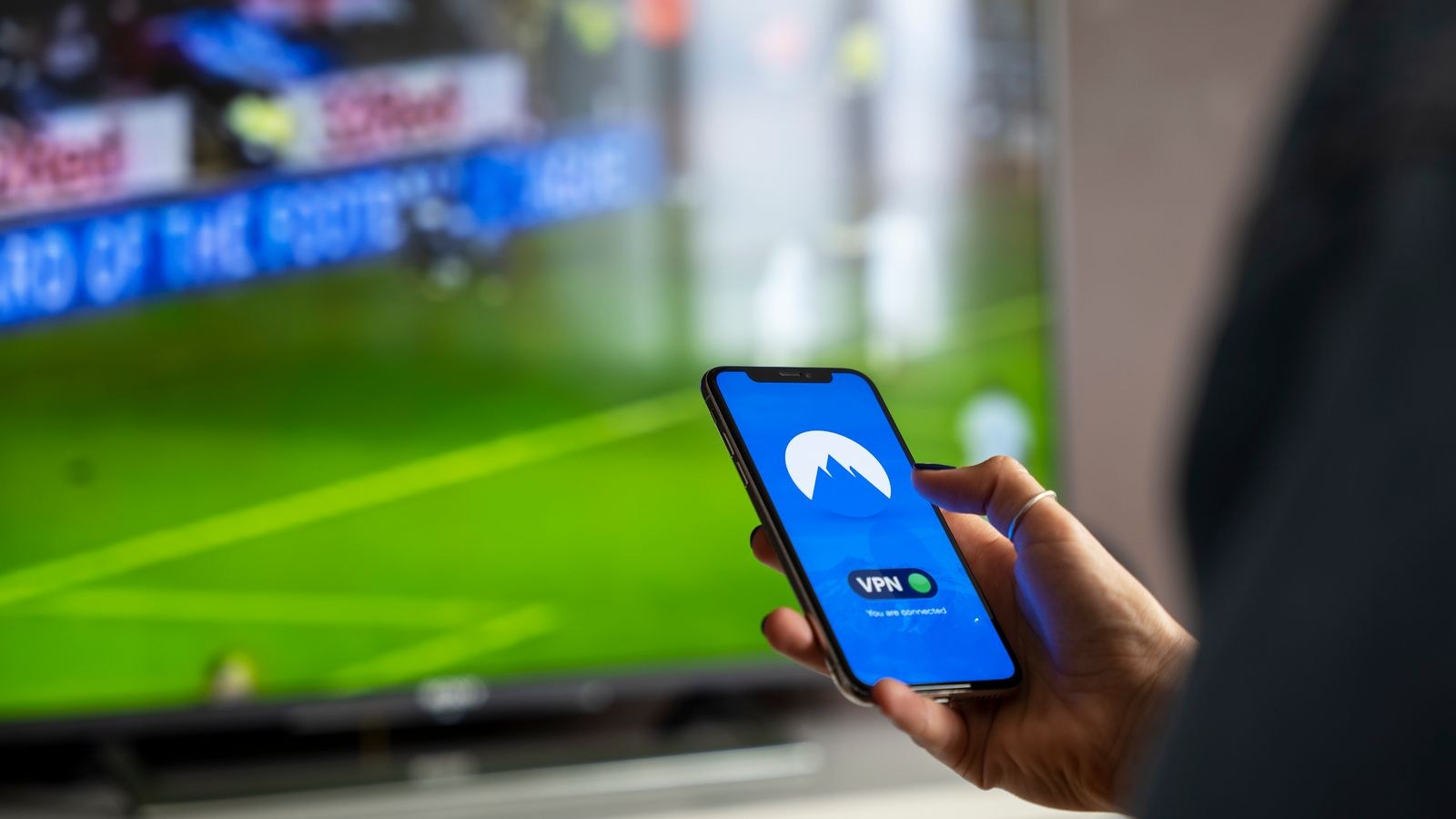 Person using a phone while streaming video on a large television screen