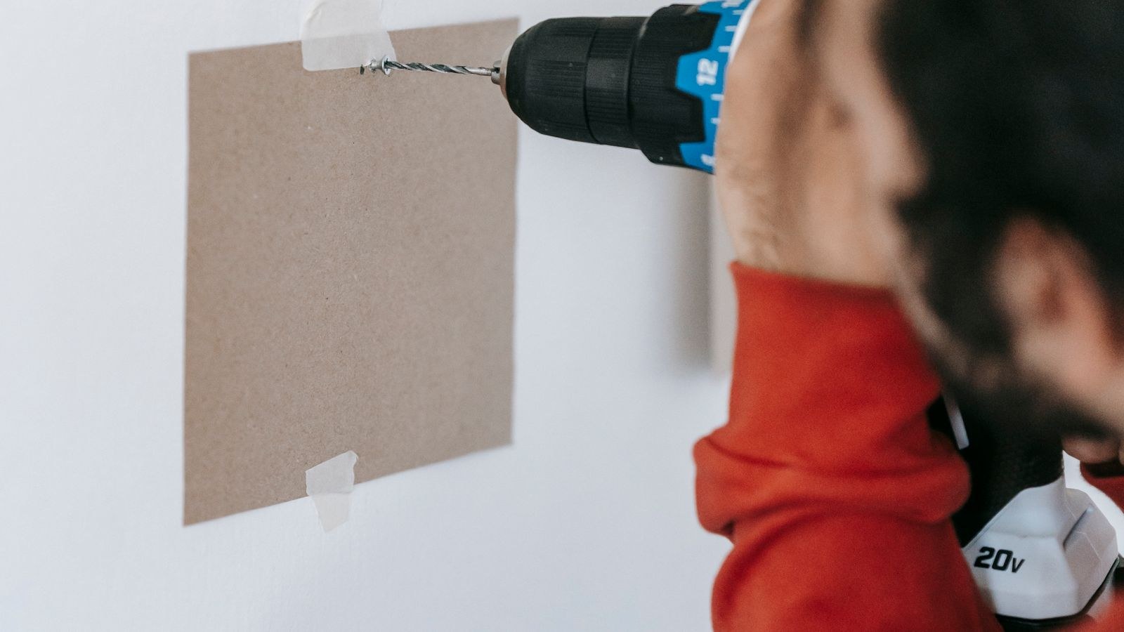 Person drilling into a wall to fit a mounting bracket