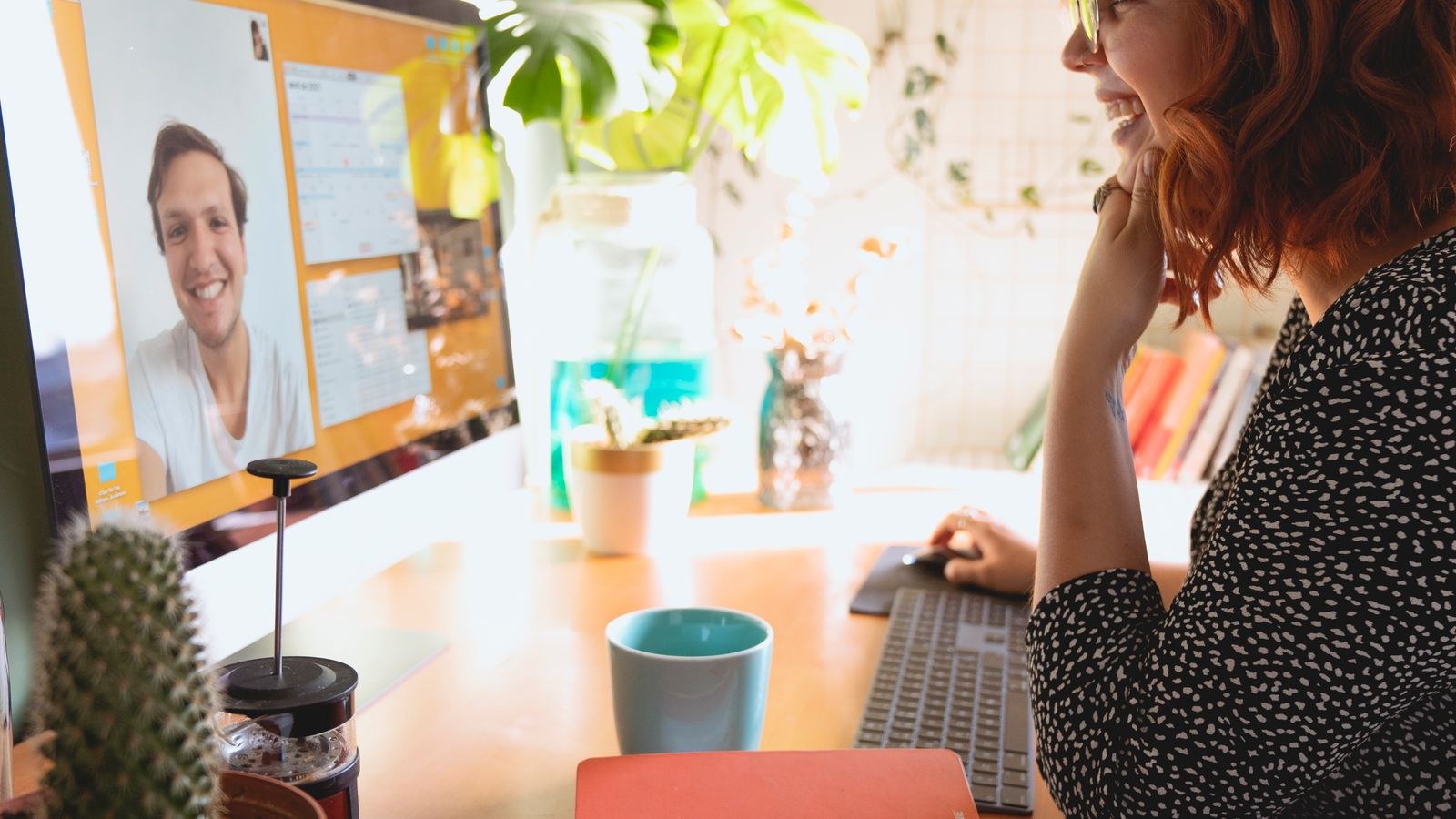 Woman on a video call at a desktop monitor setup in a home office