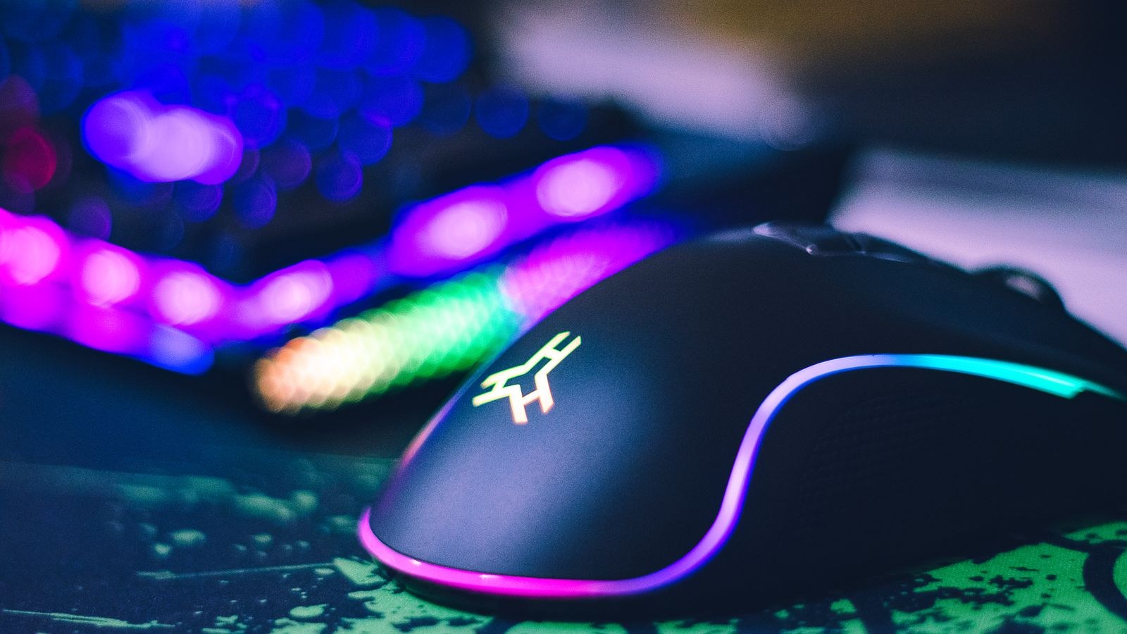 Colorful gaming mouse and illuminated keyboard on a gaming desk