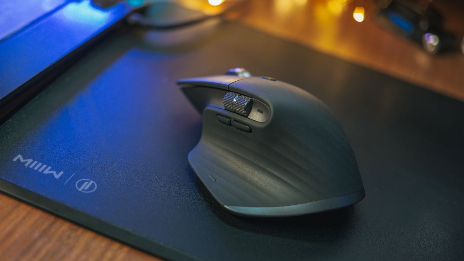 Ergonomic wireless mouse on a matte black mouse pad with ambient lighting