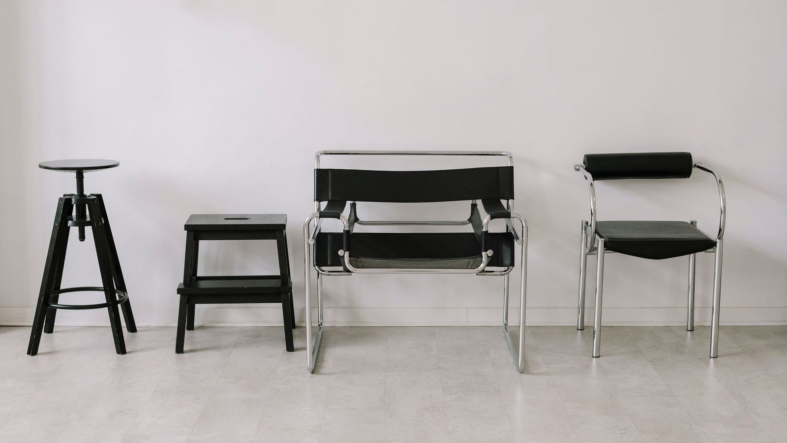 Set of black office chairs arranged against a plain white wall