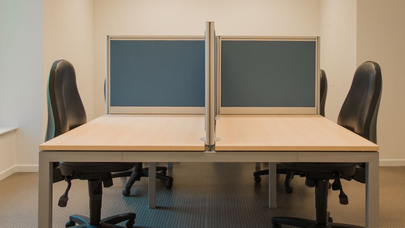 Row of ergonomic office chairs at partitioned desks in a workspace
