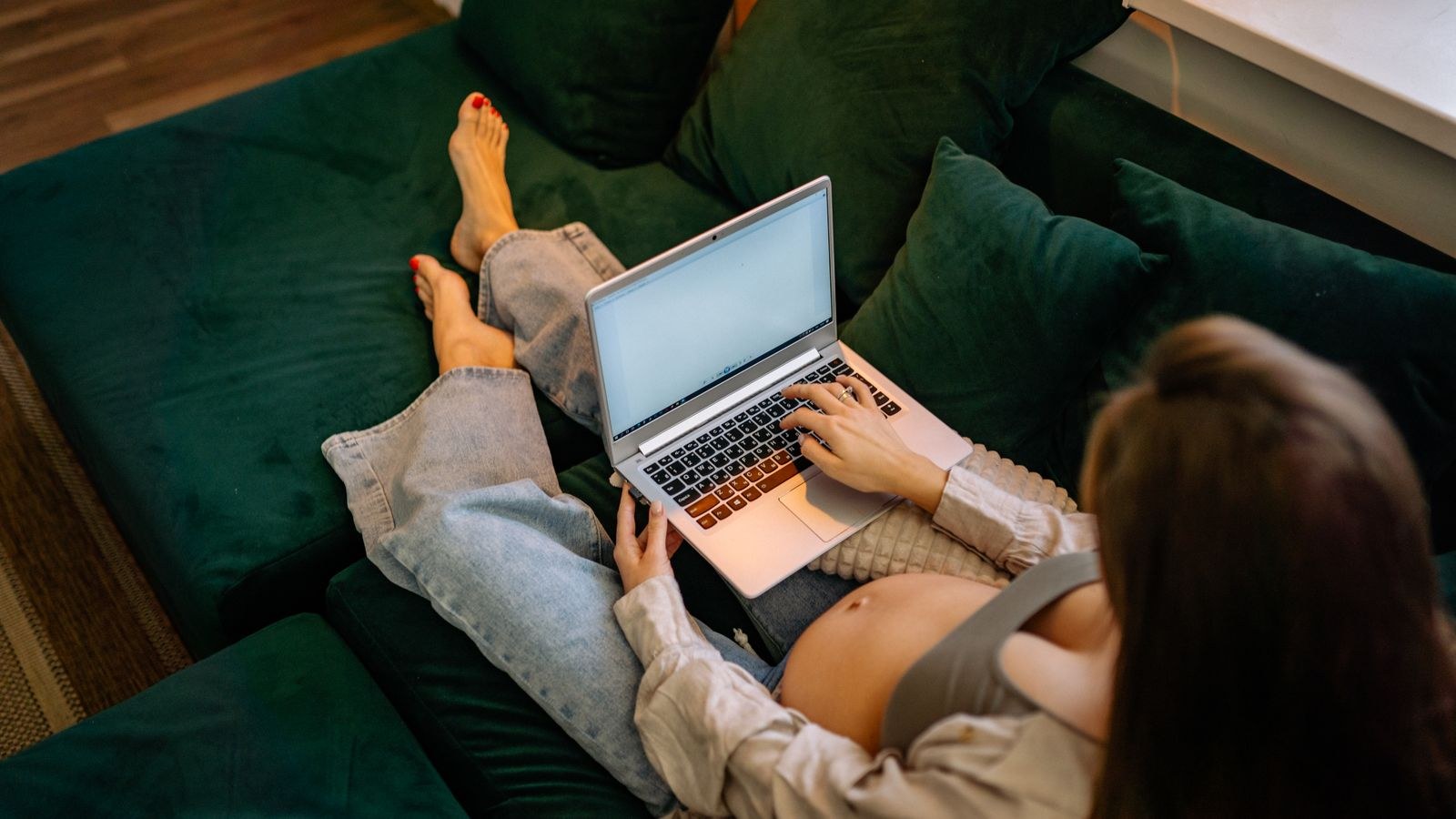 Expectant mother seated with supported posture while working remotely on a laptop
