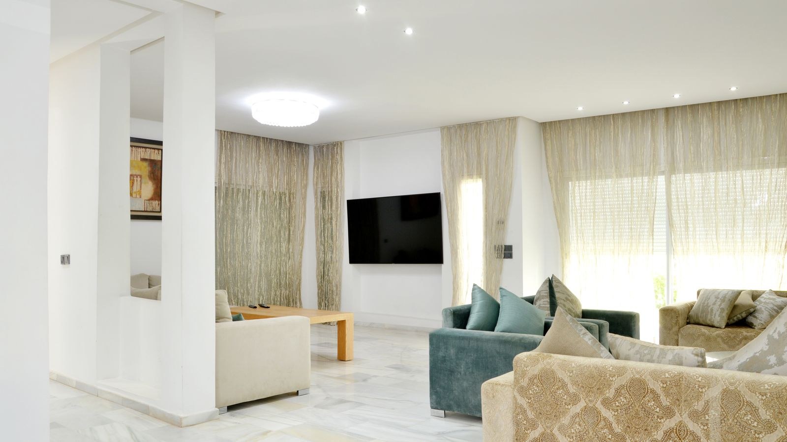 Spacious living room with sofas arranged around a large television screen