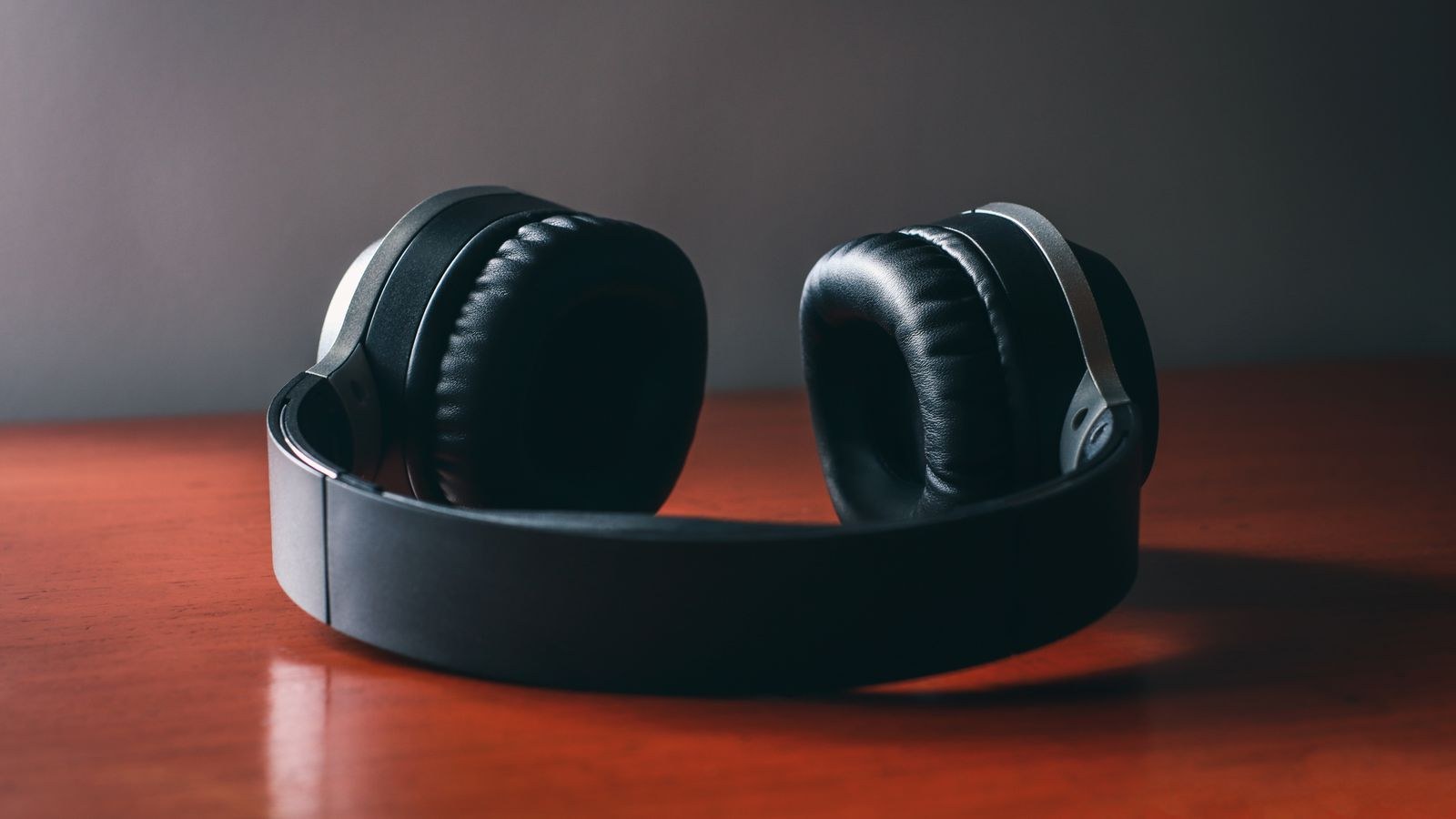 Over ear headphones on a wooden desk under soft studio lighting