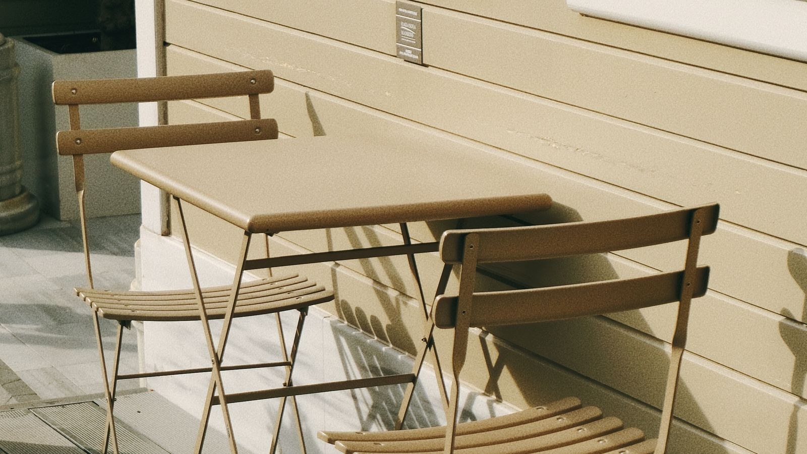 Wooden outdoor table and chairs against a weathered clapboard wall