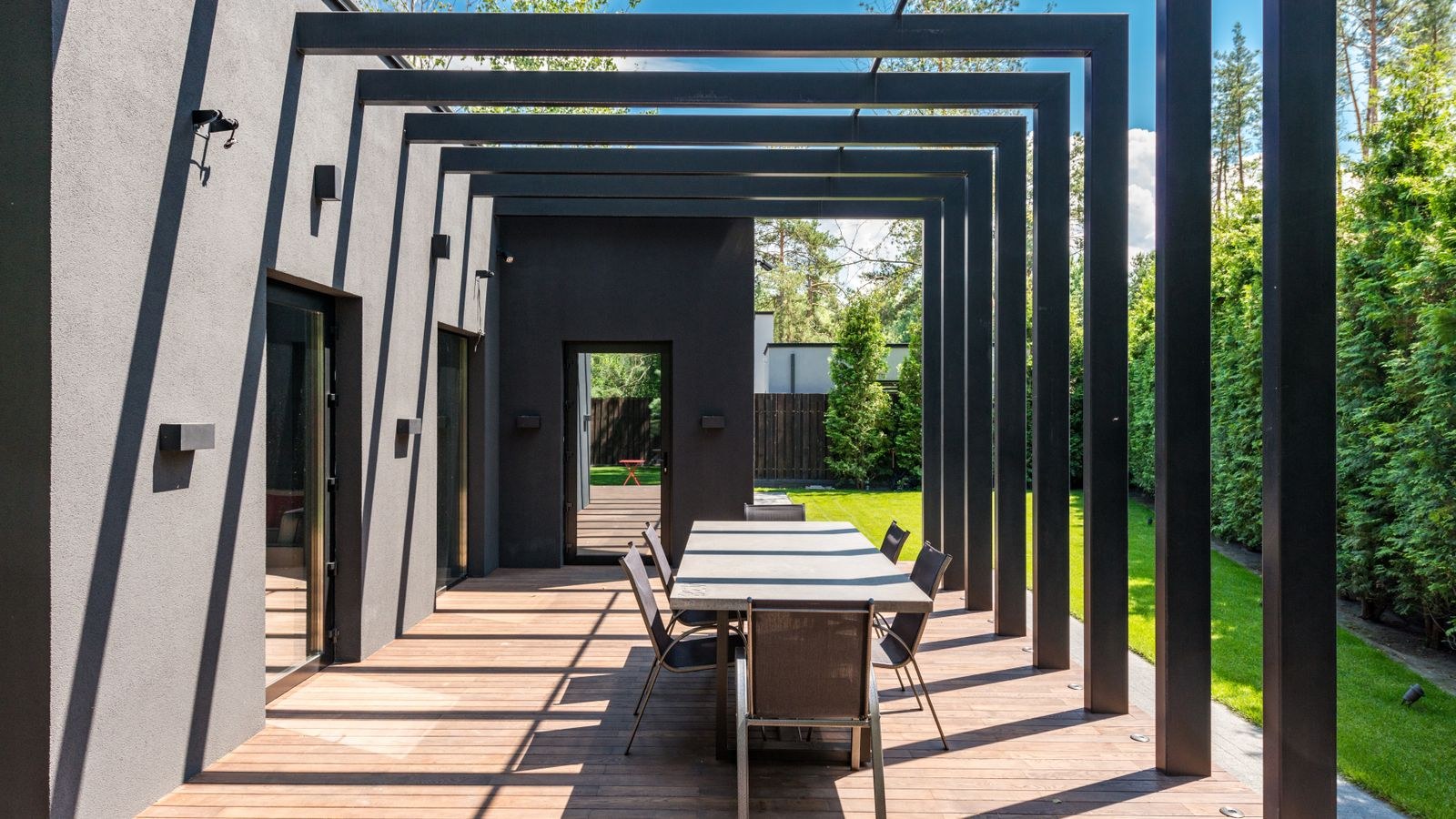 Covered patio with pergola and outdoor dining furniture ready for a TV setup