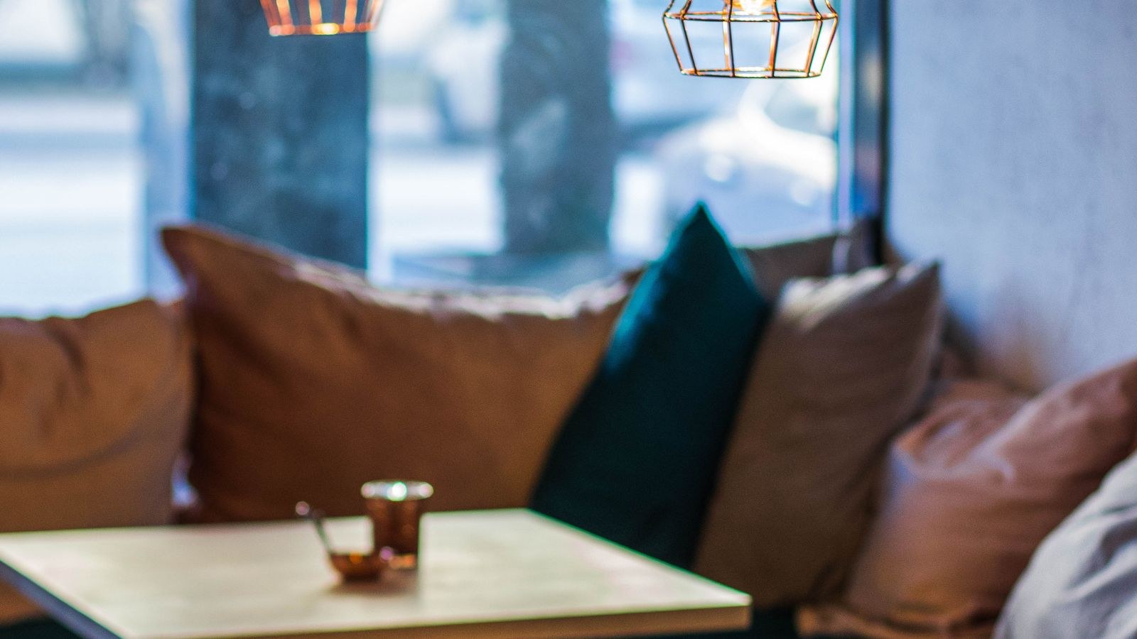 Round pendant lamps hanging evenly spaced above a warm cafe interior