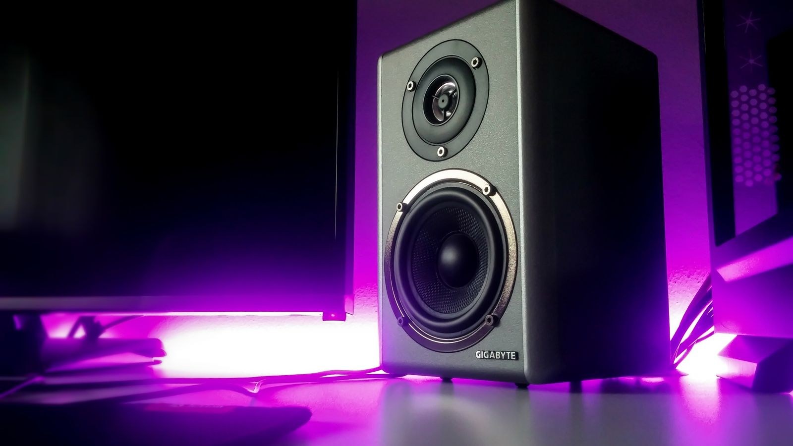 Studio monitor speaker raised on a stand at ear level near a desk