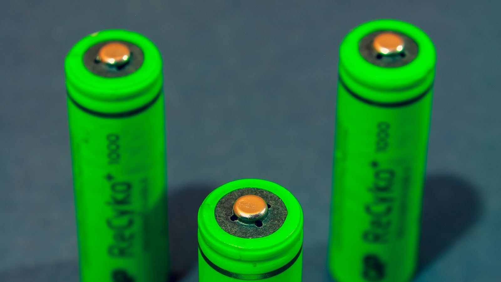 Green rechargeable NiMH batteries standing upright on a blue background