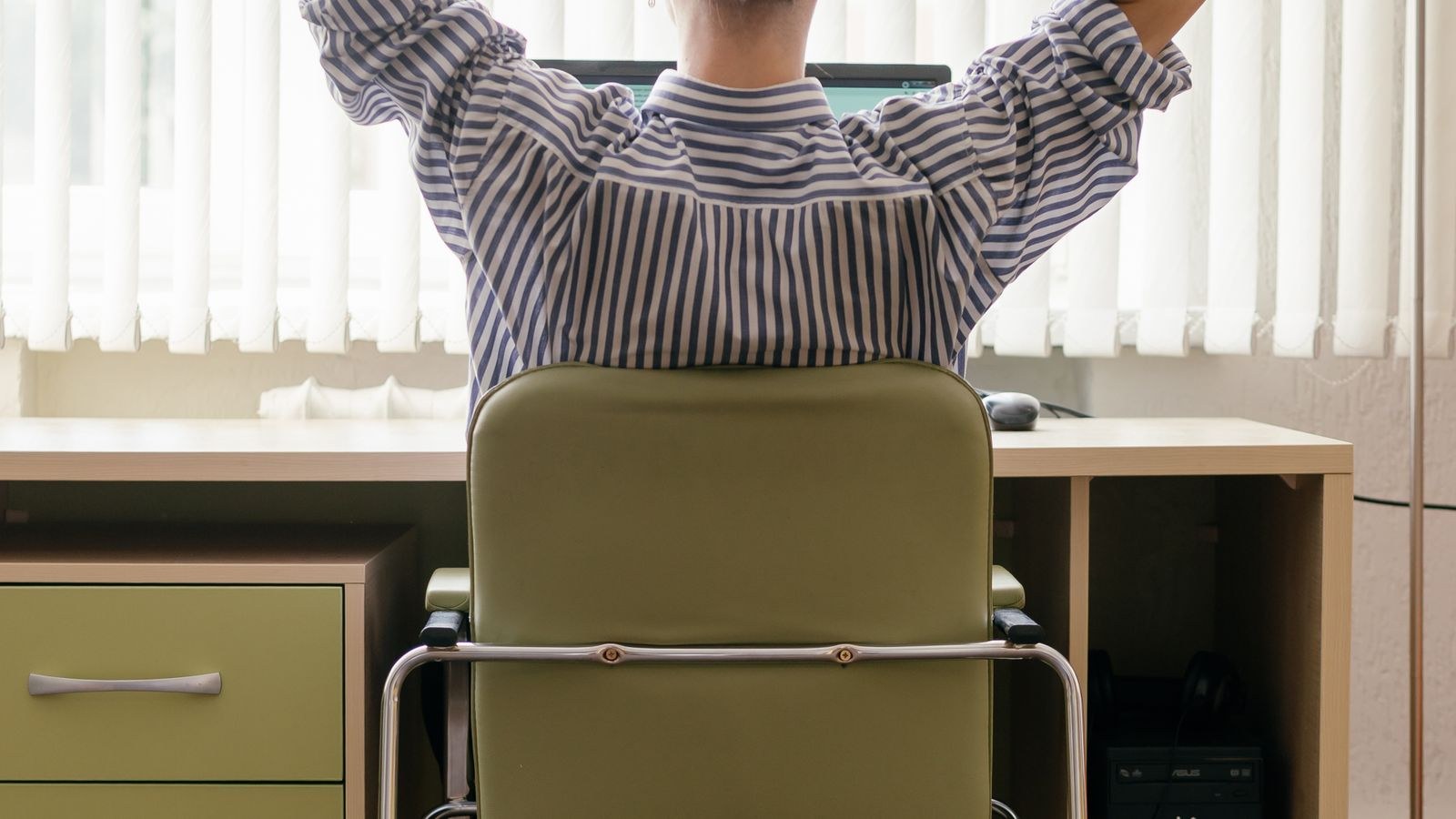Person seated at an office desk with feet flat on the floor to support leg circulation