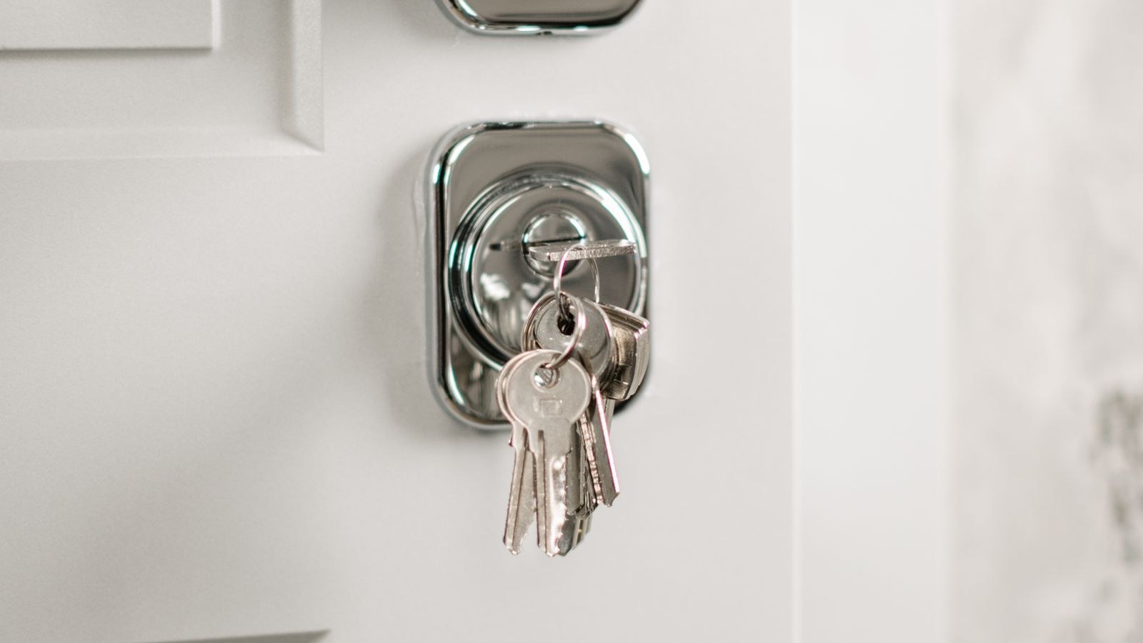 Modern silver door handle with keys hanging in the lock on a residential entry door