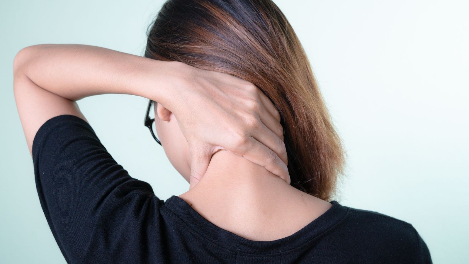 Woman massaging her neck to relieve tension in the upper trapezius muscles