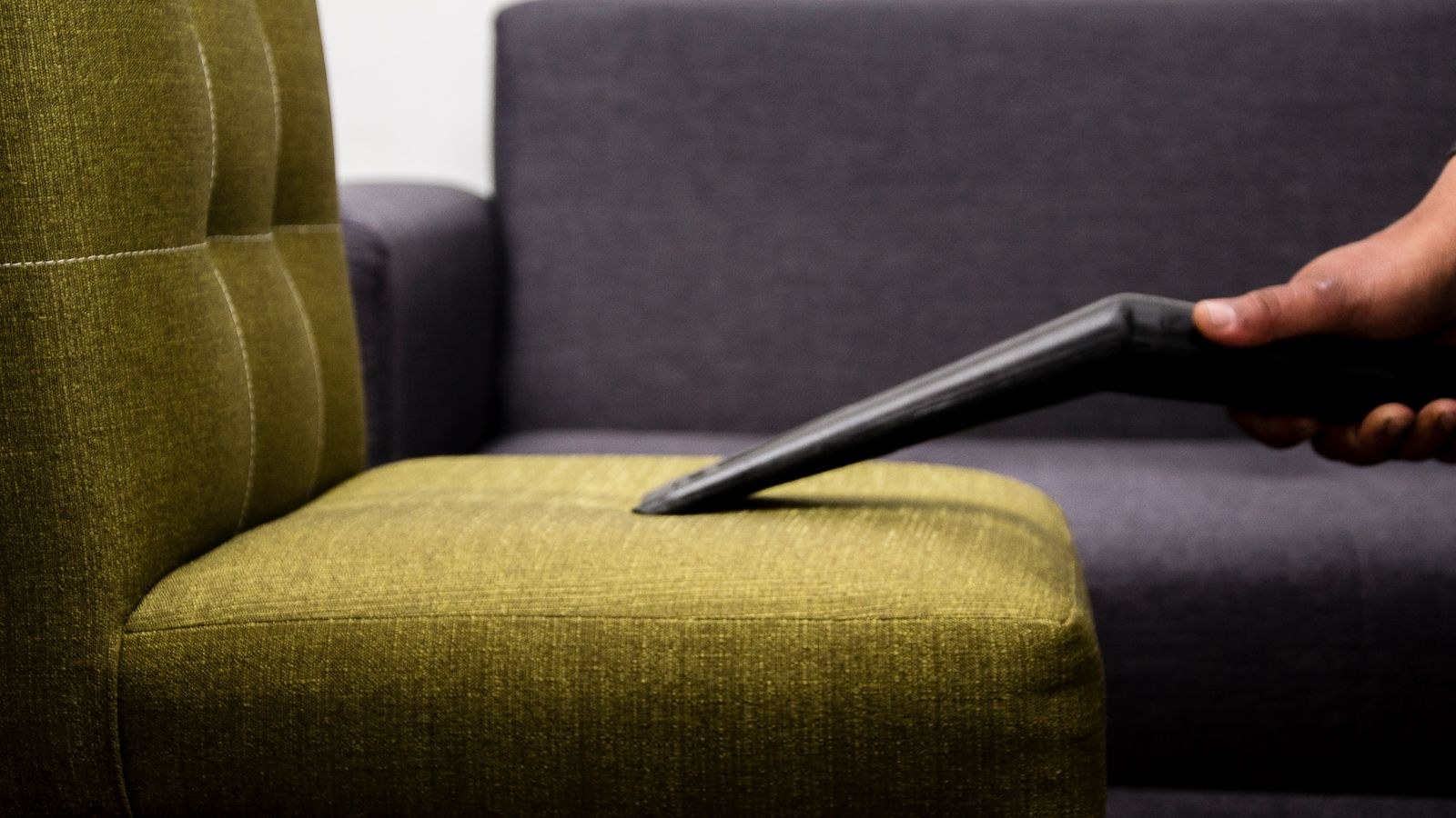 Vacuuming upholstery on a fabric chair with a brush attachment