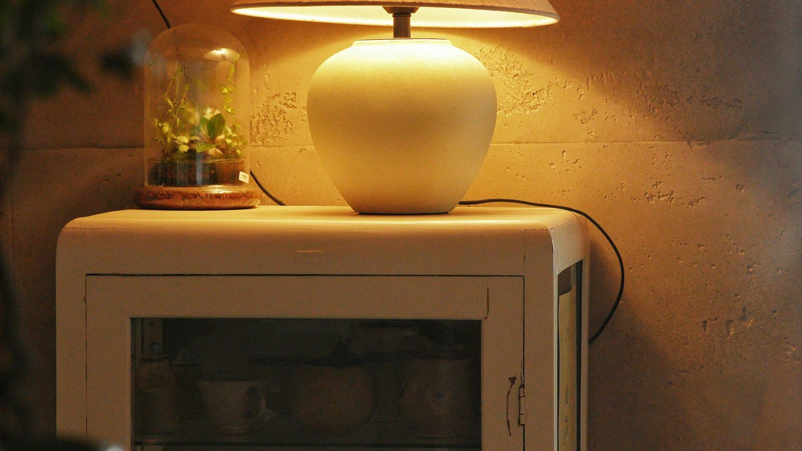Warm table lamp and decor accessories on a cabinet in a rented apartment