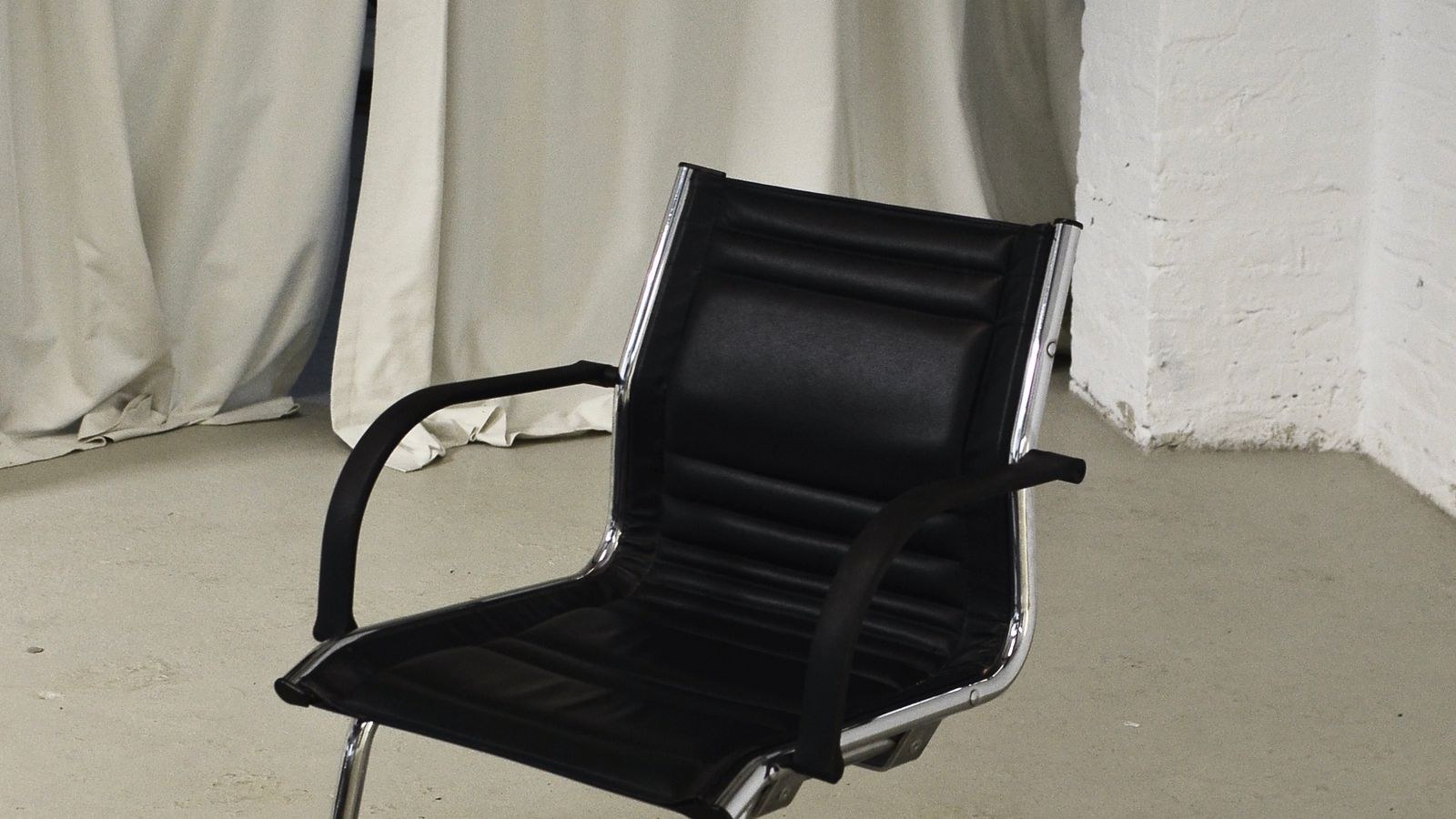 Black leather office chair with metal frame in a bright room