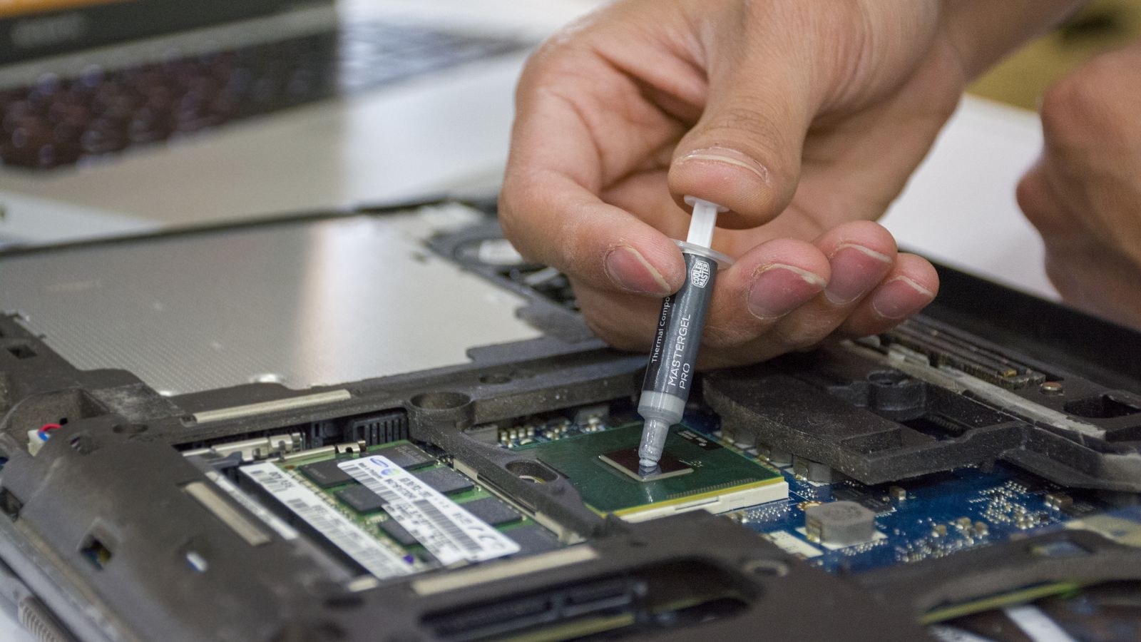 Applying fresh thermal paste to a bare GPU die during a repaste
