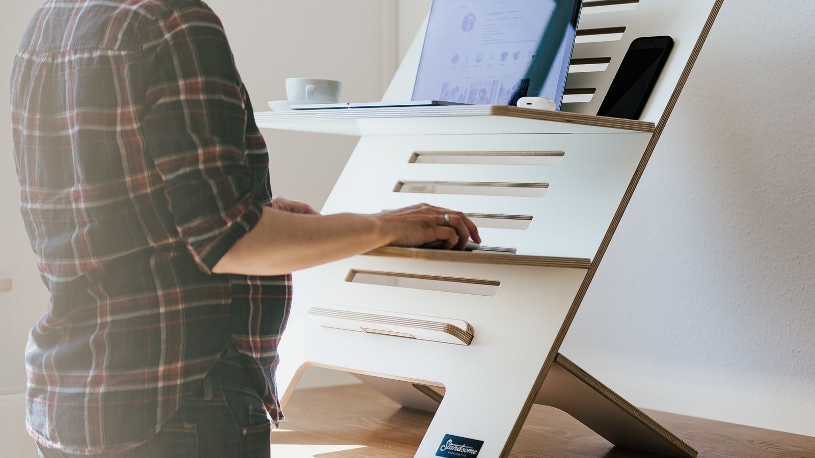 Adjustable standing desk raised to standing height beside an office window