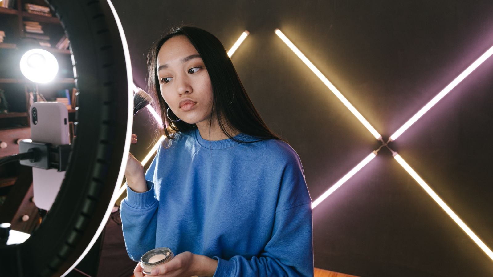 Woman applying makeup under a ring light in a modern indoor setting